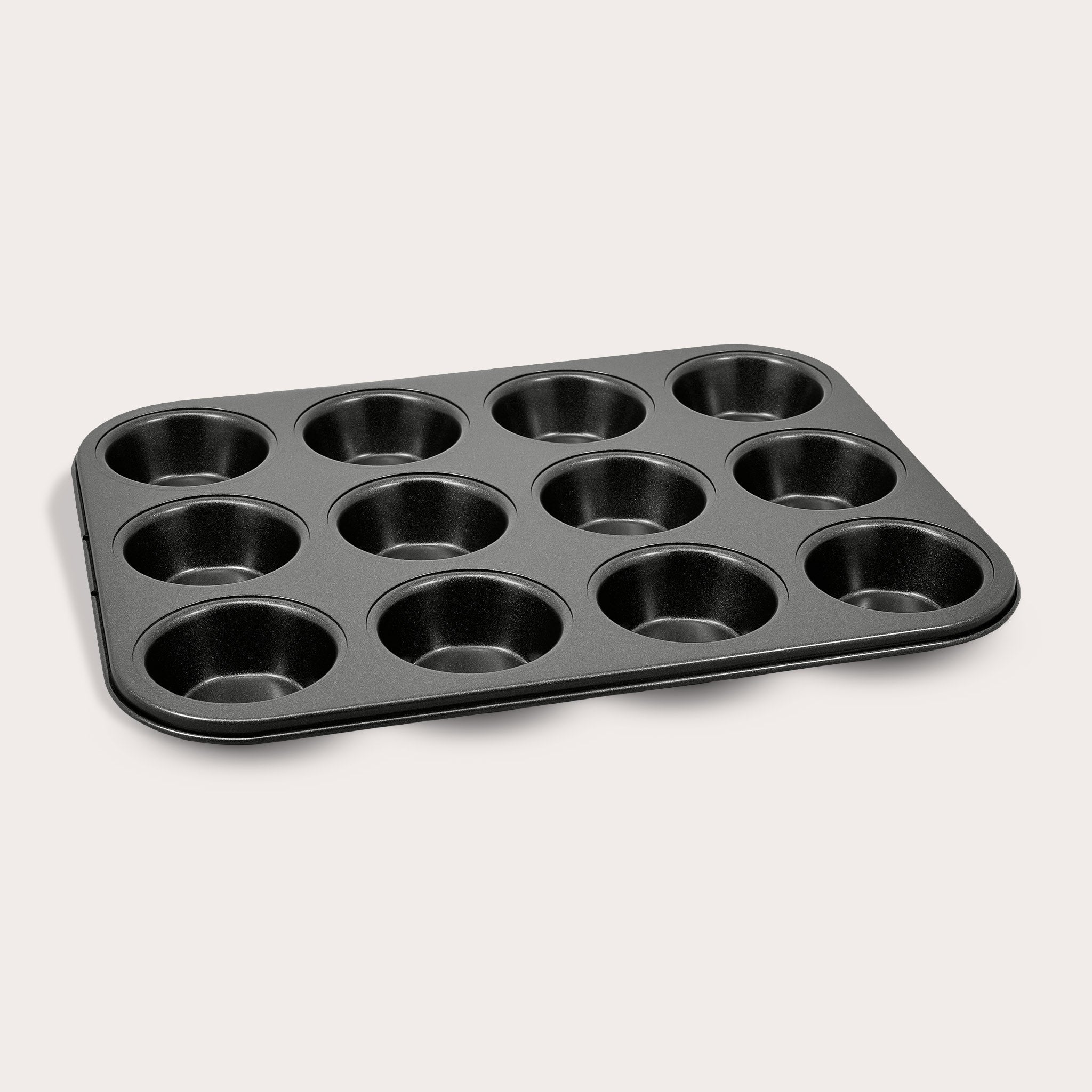 The Zyliss Non-Stick 12 Hole Muffin Pan, made from durable carbon steel and ideal for baking muffins or cupcakes, is displayed on a plain light background.