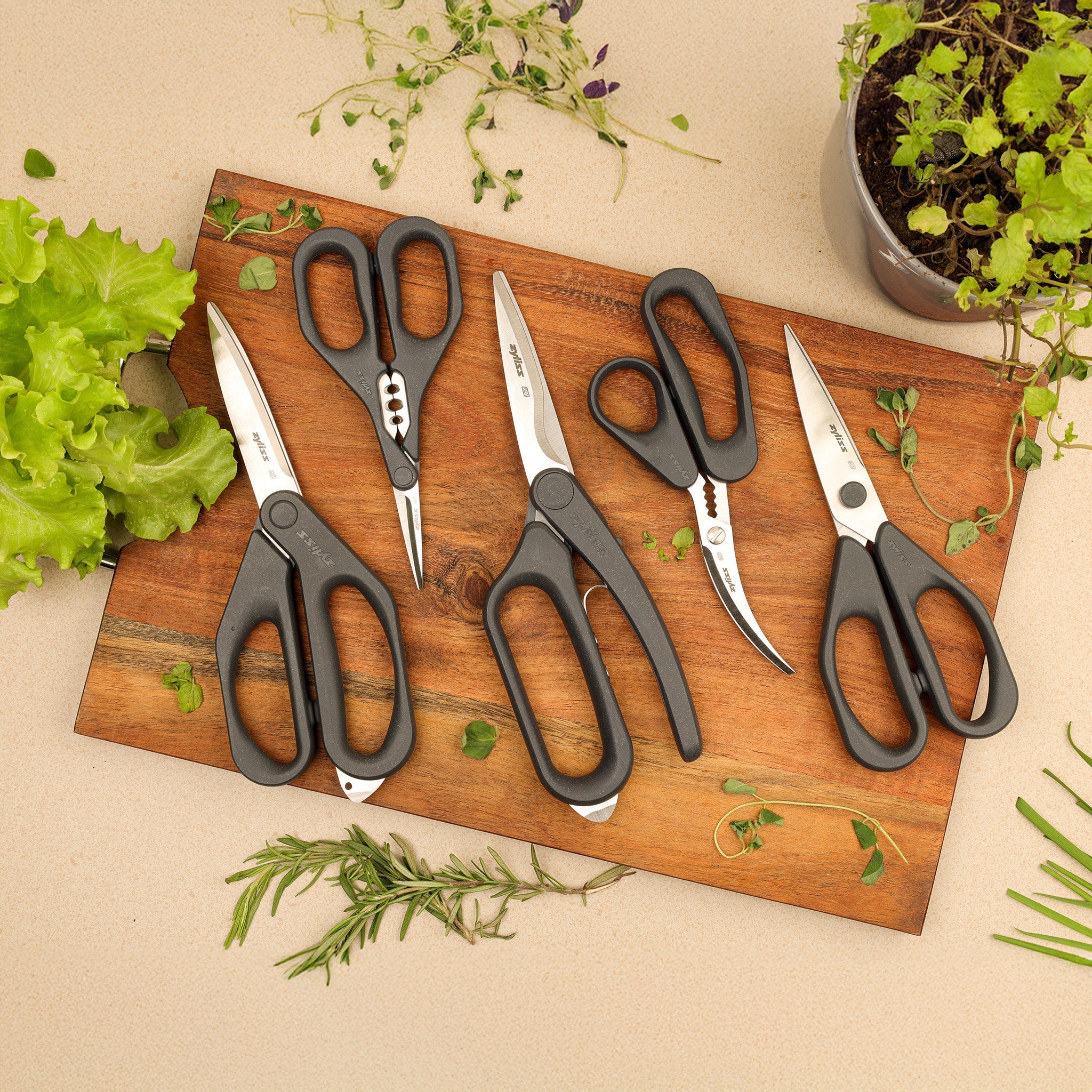 A person uses a pair of large black-handled scissors to cut a piece of white string, which is attached to a ball of twine on a light gray surface.