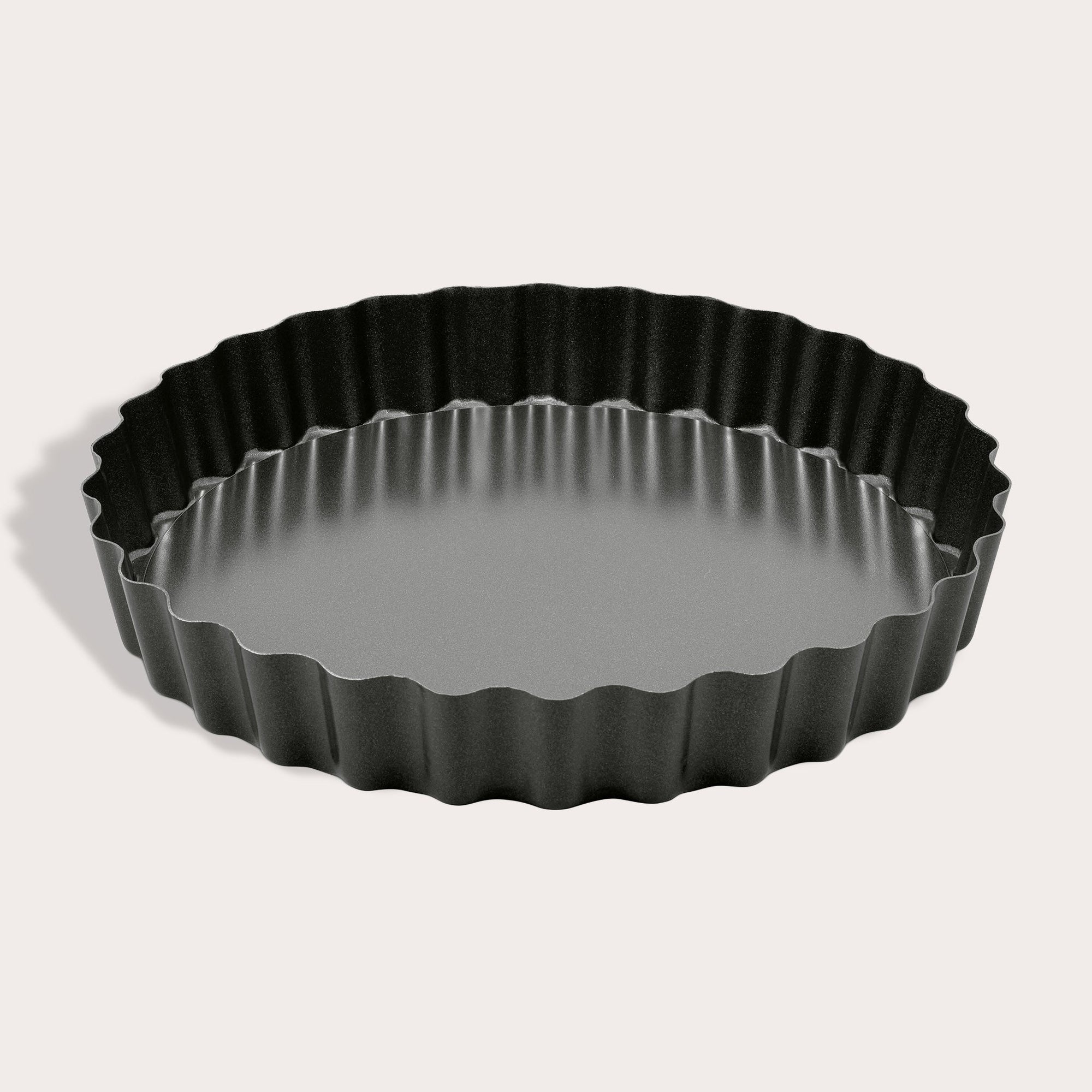 The Zyliss Non-Stick Tart Pan is round and black with fluted edges, a flat bottom, and a removable base—ideal for baking tarts or quiches. The empty pan is displayed on a light background.