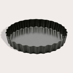 The Zyliss Non-Stick Tart Pan is round and black with fluted edges, a flat bottom, and a removable base—ideal for baking tarts or quiches. The empty pan is displayed on a light background.