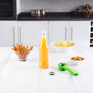 An open glass bottle of orange soda rests on a white kitchen table with pretzel sticks, potato chips, peanuts, and the Zyliss 5-Way Opener Green—a must-have kitchen tool for every gathering. 