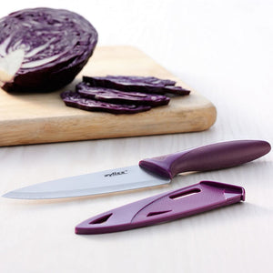 A Zyliss 3 Piece Knife Set chef’s knife with a purple handle rests on a light wooden surface beside slices of red cabbage, highlighting one of the most versatile and essential kitchen tools. 
