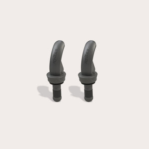 Two black, curved Zyliss Bottle Stopper 2 Piece Set items with a matte finish are displayed upright on a light beige background, featuring sleek designs that resemble wireless earbuds and small brand markings on their surfaces.