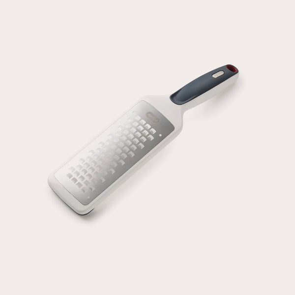 The Zyliss Smooth Glide Coarse Grater features a sharp stainless steel blade, black and red handle, is dishwasher safe, and is shown on a light background. 