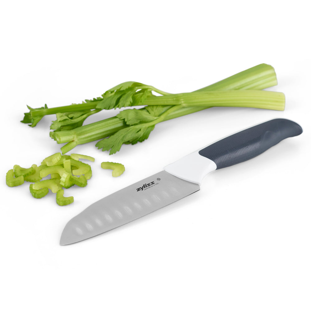 A Zyliss Comfort Mini Santoku Knife 12cm / 4¾ with a white and black ergonomic handle and matching black blade cover is placed beside it, set against a plain light background. 