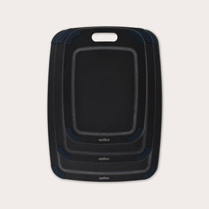 The Zyliss Wood Fibre Cutting Boards set features three nested black boards in different sizes, each with a handle slot and dark gray corner grips, made from eco-friendly recycled wood fibres and shown on a light background. #set of 3