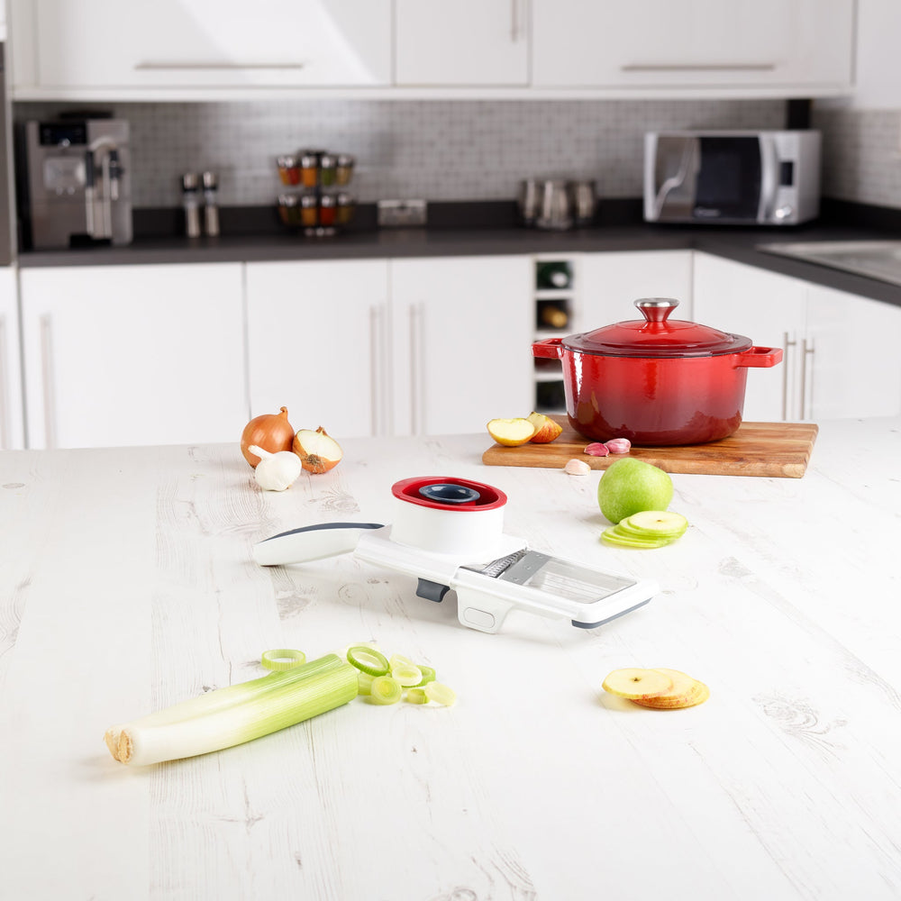 The Zyliss Easy Control Handheld Slicer is a white and black tool with a red and black food holder, designed for safe, even vegetable slicing, and features an adjustable thickness selector for custom cuts. 