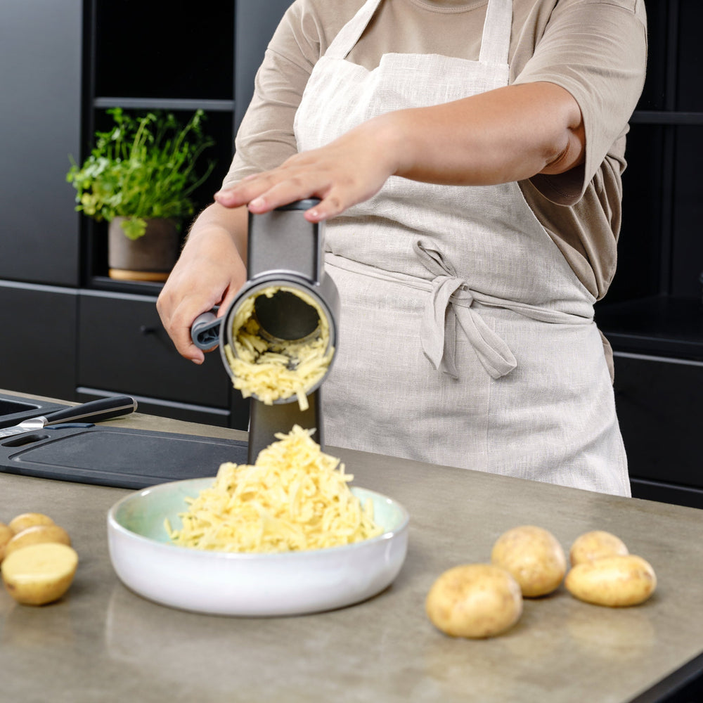 The Zyliss Puree Drum Gourmet, a stainless steel rotary grater attachment featuring large circular and oval holes, is designed for use with kitchen appliances and displayed on a plain light background. 