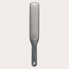 #belugagrey The Zyliss Rasp Grater is a long, rectangular foot file with a gray handle and textured metal surface for removing calluses and dead skin. The handle features a hanging hole for easy storage. 