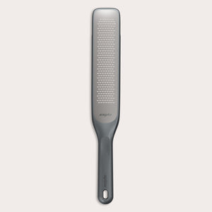 #belugagrey The Zyliss Rasp Grater is a long, rectangular foot file with a gray handle and textured metal surface for removing calluses and dead skin. The handle features a hanging hole for easy storage. 