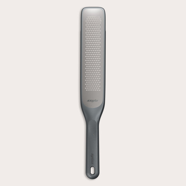 #belugagrey The Zyliss Rasp Grater is a long, rectangular foot file with a gray handle and textured metal surface for removing calluses and dead skin. The handle features a hanging hole for easy storage. 