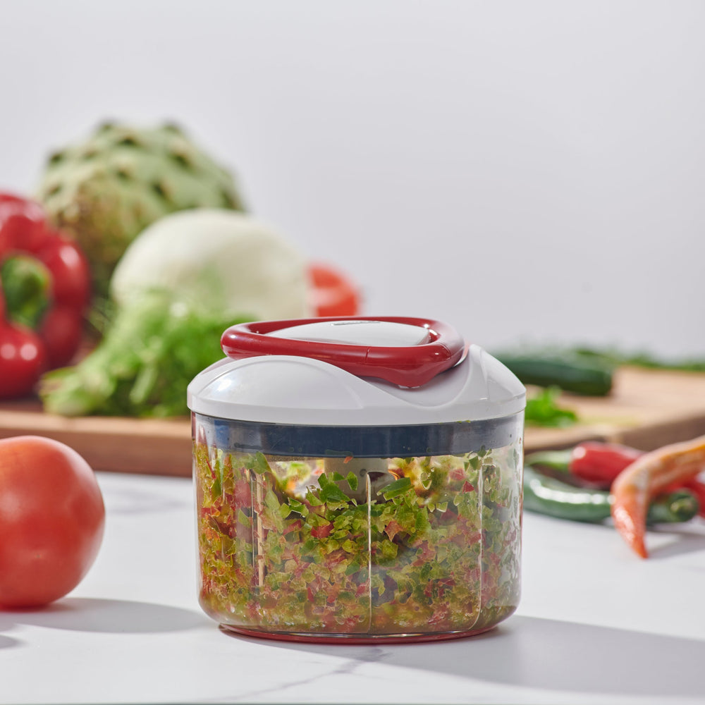 The Zyliss Easy Pull Food Processor is a compact, hand-powered chopper with a clear plastic container, white and red lid, and visible metal blades for easy food prep without electricity. 