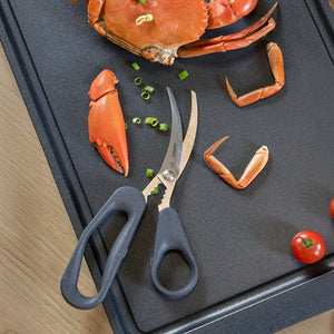 Zyliss Seafood Scissors rest on a black tray beside crab claws, cooked crab, chopped green onions, and cherry tomatoes—ideal for easy shellfish prep.