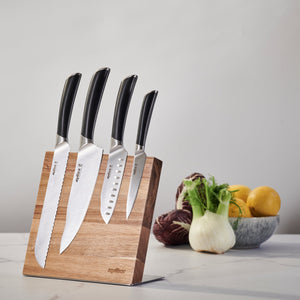 The Zyliss Comfort Pro Magnetic Knife Block displays four kitchen knives with black handles for efficient storage, with a bowl of vegetables and lemons on the countertop in the background. 