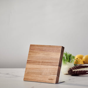 The Zyliss Comfort Pro Magnetic Knife Block stands on a white marble countertop, providing stylish knife storage. Lemons, fennel, and radicchio are arranged on the right against a plain light gray wall. 