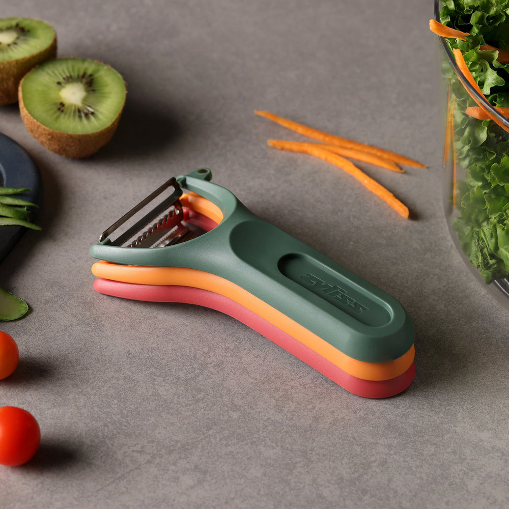 The Zyliss 3 Piece Y Peeler Set features ergonomic handles and Swiss-made stainless steel blades in green, orange, and red, stacked vertically against a plain light background.