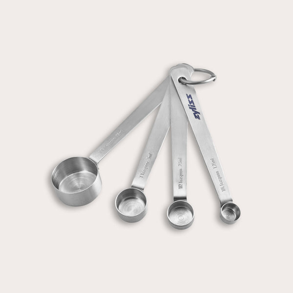 The Zyliss Stainless Steel Measuring Spoons set includes four essential kitchen tools, connected by a metal ring and shown on a plain light background. 