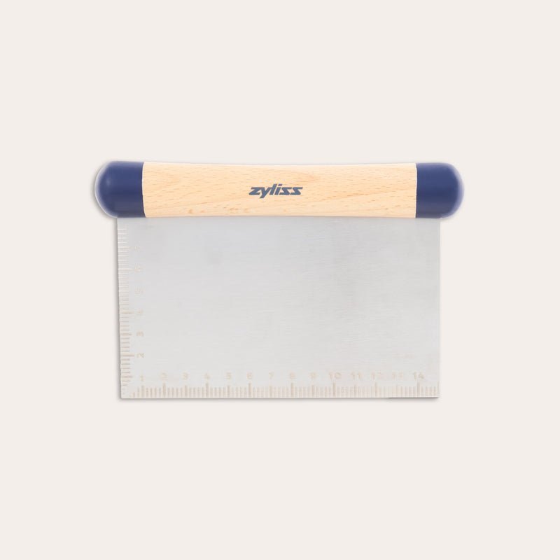 The Zyliss Beech Wood Bench Scraper features a beech wood handle, blue plastic ends, and a metal blade with an etched ruler—a versatile tool for baking tasks.