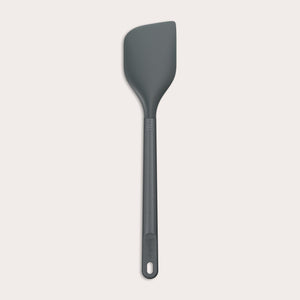 A dark gray Zyliss Spatula with a long handle and a slightly angled, heat-resistant silicone head is displayed on a plain white background. #Large