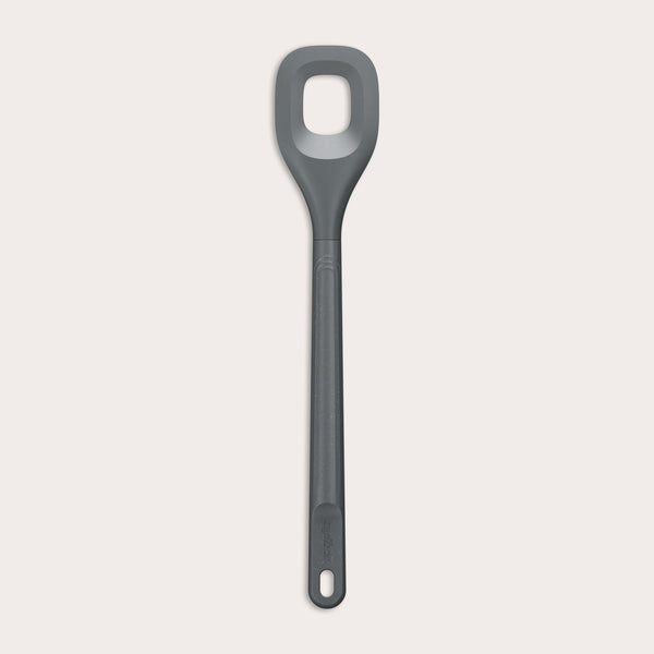The Zyliss Square Mixing Spoon is a gray, heat-resistant silicone utensil with a long handle and a rectangular hole in the head. Shown on a plain light background, its dishwasher safe for easy cleaning. 