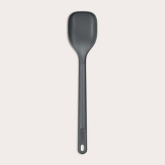 #medium The Zyliss Spoon is a dark gray, heat-resistant silicone utensil with a long handle and end hole, ideal for cooking or serving. Shown against a plain light background. #Medium