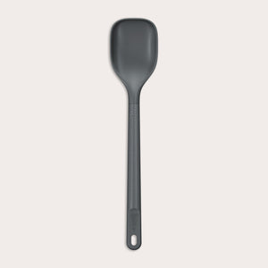 #medium The Zyliss Spoon is a dark gray, heat-resistant silicone utensil with a long handle and end hole, ideal for cooking or serving. Shown against a plain light background. #Medium