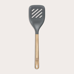 The Zyliss Oak Wood Slotted Turner is a kitchen essential with a wide, dark gray head and light oak wood handle, shown on a plain white background.