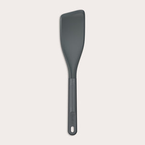 The Zyliss Easy Lift Turner is a gray, heat-resistant silicone utensil with a rectangular, angled head and long handle with hanging hole—perfect for non-stick cookware. Shown on a plain white background. 