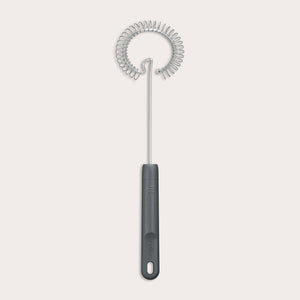The Zyliss Gravy Whisk features a metal spiral and a dark plastic handle with a hanging hole. It is heat-resistant and shown against a plain light background. 