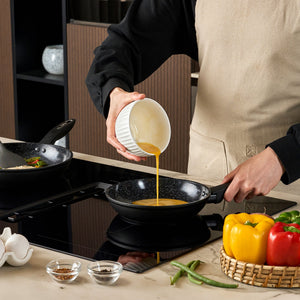 #20cm/8"
Wearing a beige apron, a person pours beaten eggs from a white bowl into the Zyliss Ultimate Ceramic Fry Pan on the stove. Nearby are bell peppers, green beans, eggshells, and bowls of spices.