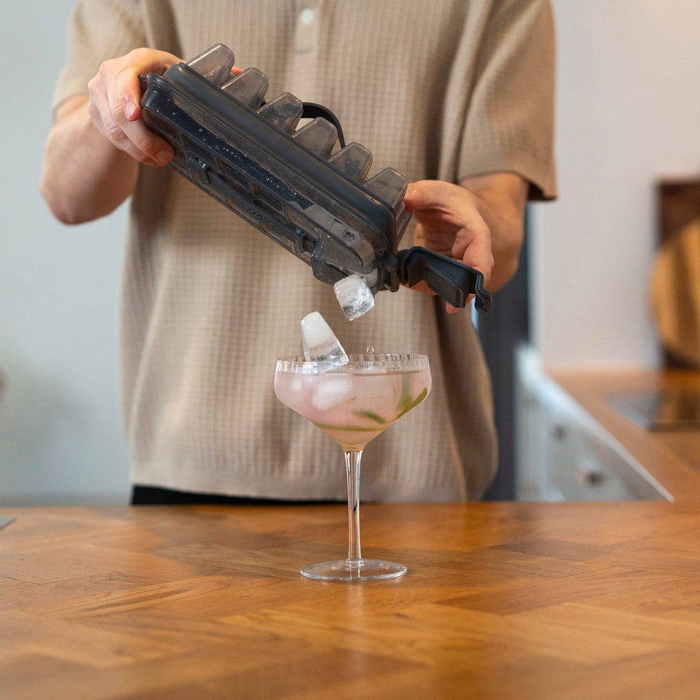 A rectangular, transparent plastic lid for the Zyliss Press & Pull Ice Cube Tray with a gray foldable handle, textured grid pattern, and "Zyliss" embossed on top, shown on a light background.