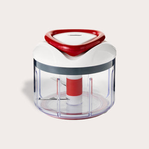 The Zyliss Easy Pull Food Processor is a compact, hand-powered chopper with a clear plastic container, white and red lid, and visible metal blades for easy food prep without electricity. 