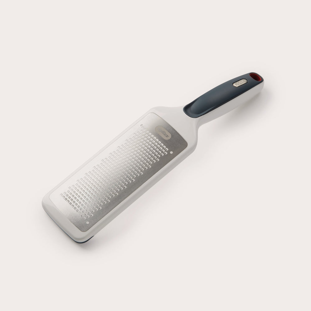The Zyliss Smooth Glide Fine Grater features a stainless steel blade and an ergonomic black and gray handle, ideal for grating cheese, vegetables, or zesting lemons. Pictured here against a plain white background. 