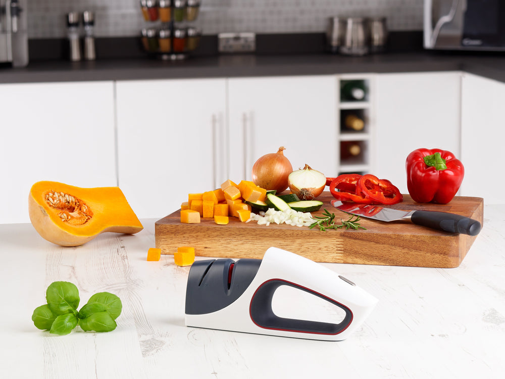 The Zyliss Control Knife Sharpener is a modern handheld sharpener for kitchen knives, featuring a white and gray body with red accents, two sharpening slots (including ceramic), shown against a plain light background. 