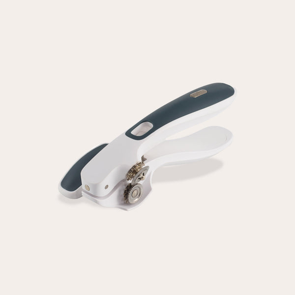 The Zyliss Lock & Lift Can Opener, shown on a plain light background, features white and dark gray colors, a large ergonomic handle, locking mechanism, and rotating cutting wheel. 