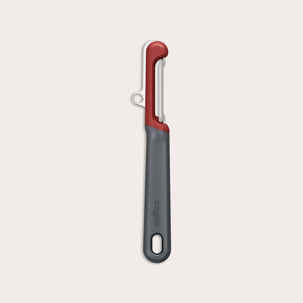 The Zyliss Soft Skin Peeler features a dark gray handle with a small end hole, a red top, and a horizontal stainless steel blade. This eco-friendly peeler is displayed on a plain light background. 