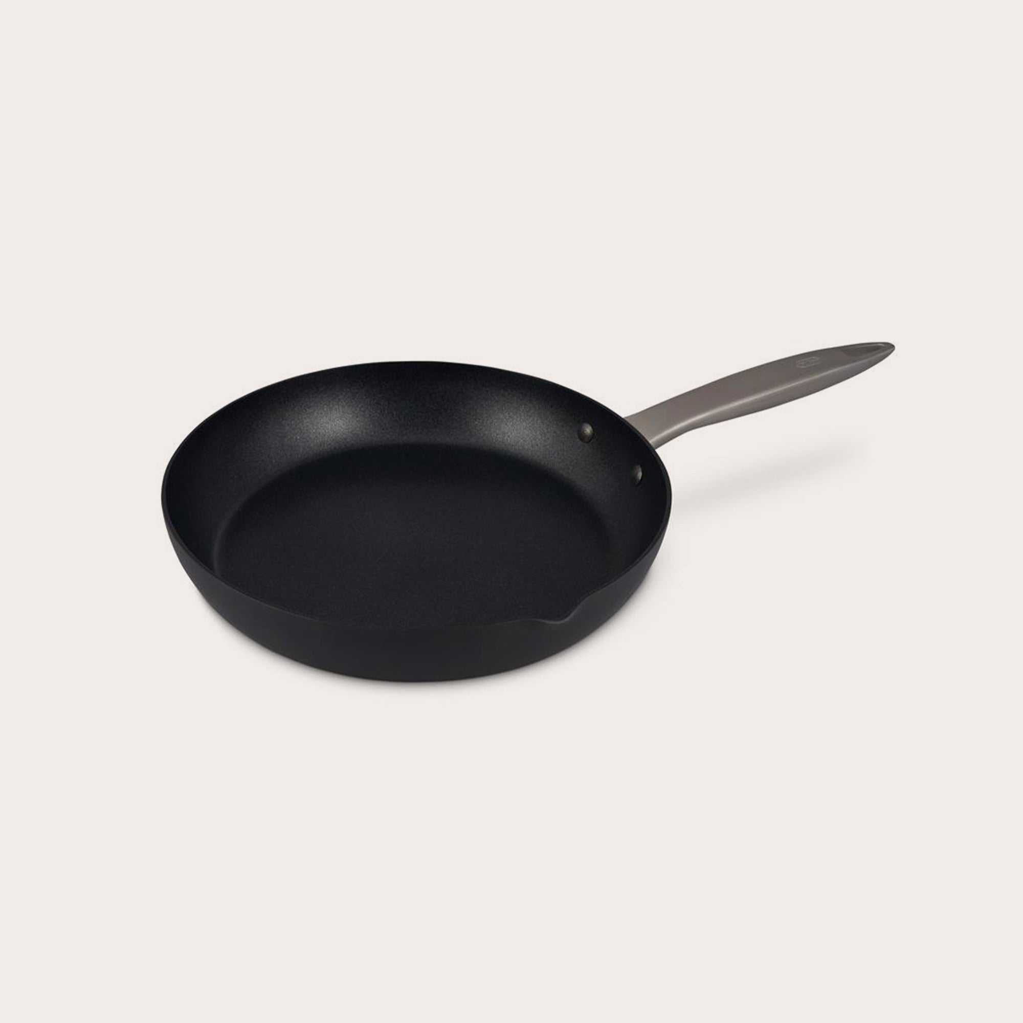 The Zyliss Ultimate Pro Non-Stick Frying Pan With Pouring Lip, made of hard-anodized aluminium with a metal handle, sits on a plain white background, viewed at a slight angle. #24cm/9½"