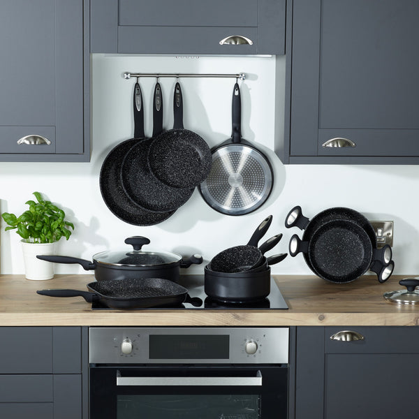 A modern kitchen with grey cabinets, a wooden countertop, and Zyliss Ultimate Non-Stick Frying Pans with Swiss coating in black speckle displayed on the stove and wall. A potted basil plant adds a touch of green on the counter. #20cm/8"