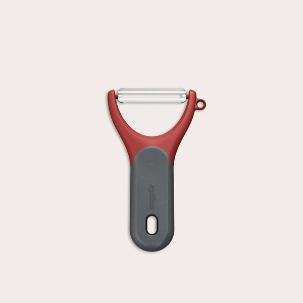 The Zyliss Soft Skin Y Peeler, shown against a white background, features a red and gray ergonomic grip, wide handle, and stainless steel blade for eco-friendly peeling. 