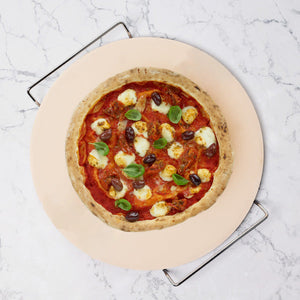 A homemade pizza with tomato sauce, mozzarella, black olives, and basil sits on the Zyliss Ceramic Baking Stone atop marble, featuring a golden crust. 