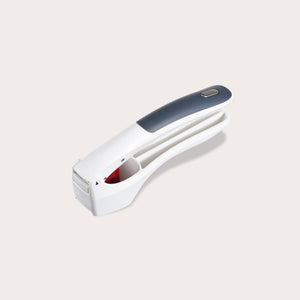 The Zyliss Easy Clean Garlic Press, featuring ergonomic white and gray handles with a soft grip, is displayed on a light gray background. 