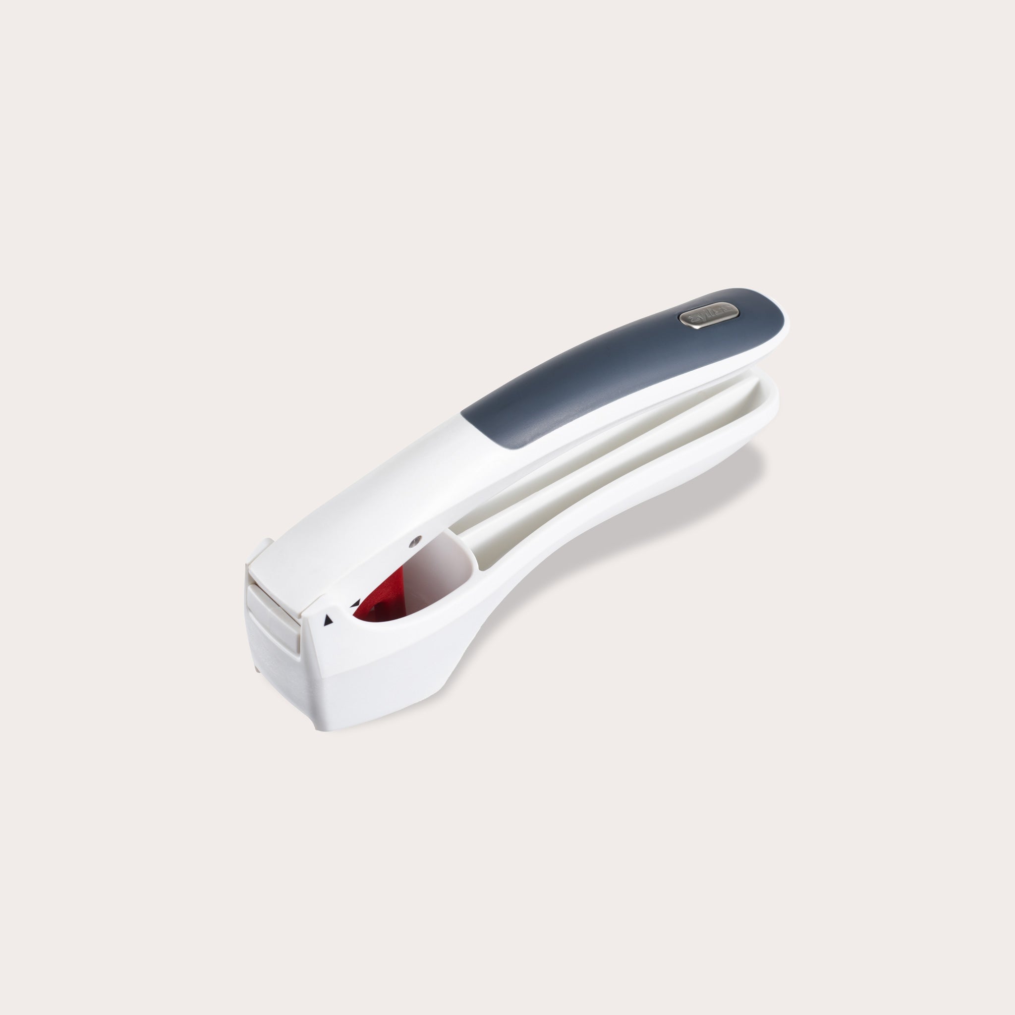 The Zyliss Easy Clean Garlic Press, featuring ergonomic white and gray handles with a soft grip, is displayed on a light gray background. 